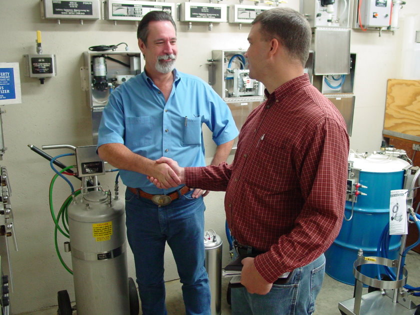 Employees shaking hands in front of equipment