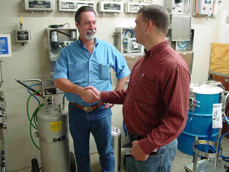 Employees shaking hands in front of equipment